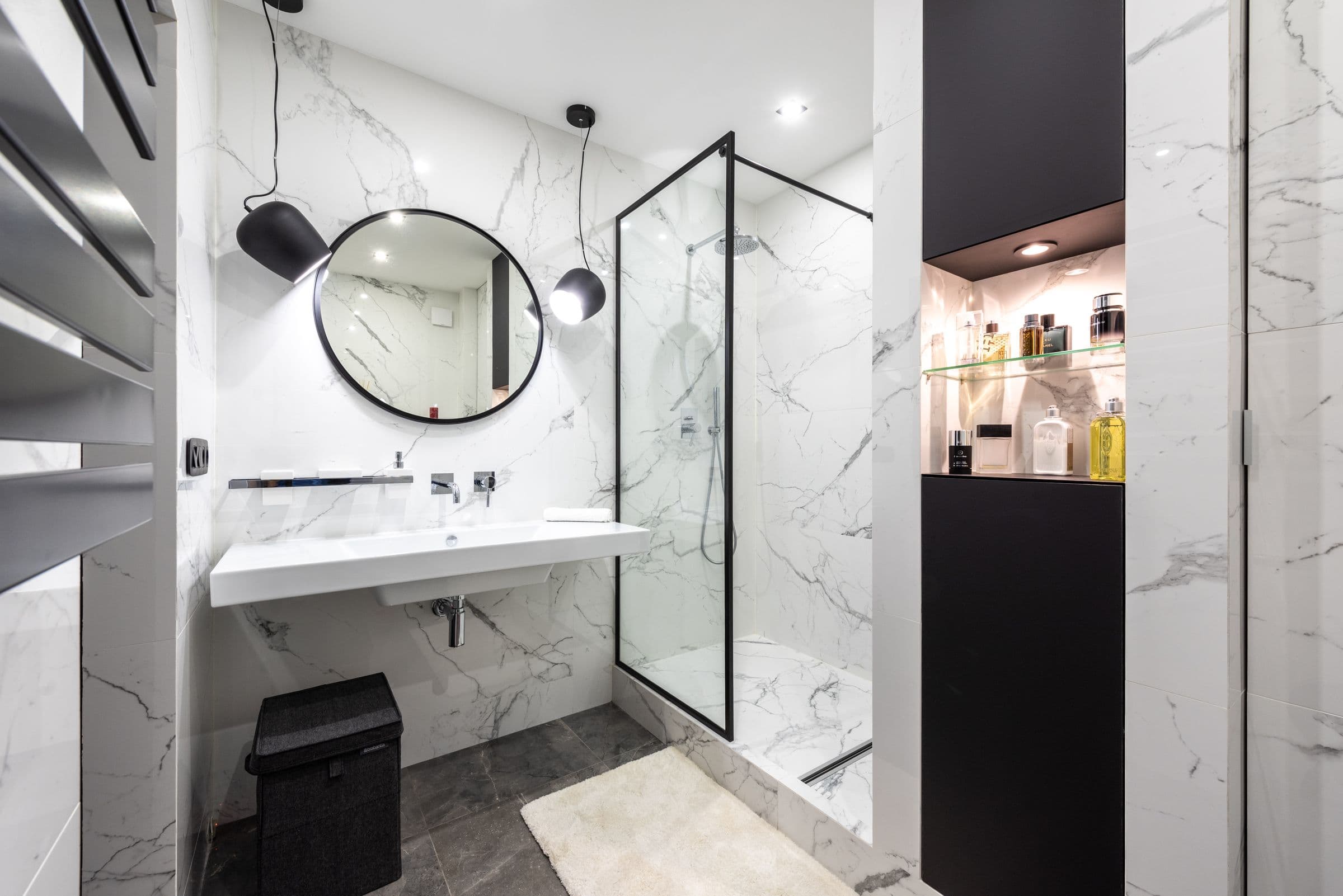 Modernes Bad mit Glasdusche, rundem Spiegel und Marmoroptik
